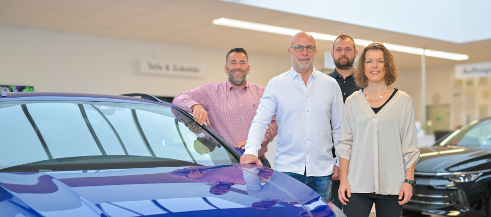 Das Verkaufsteam aus vier Personen an einem Fahrzeug